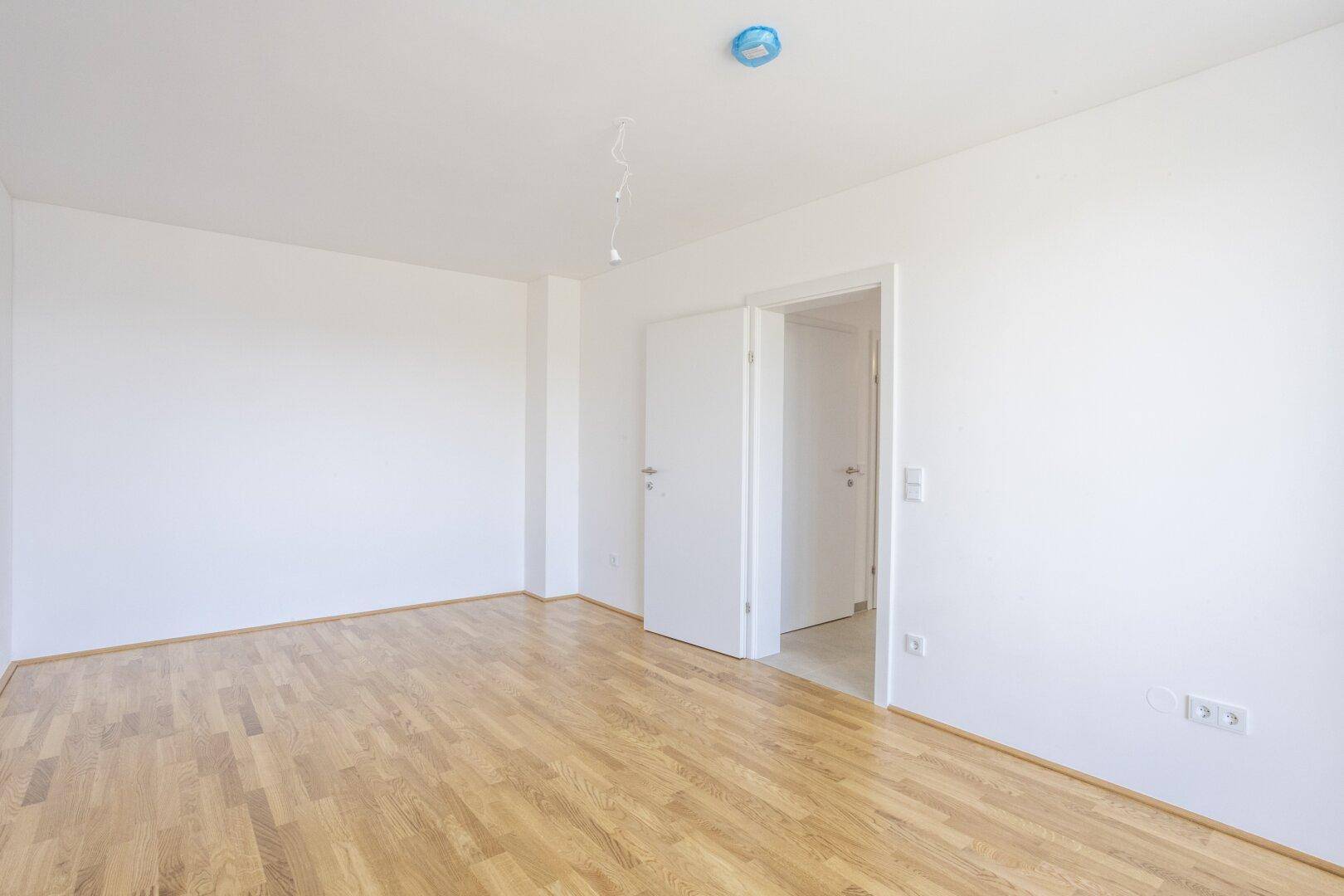 Geräumiges Schlafzimmer mit Parkettboden und weißen Wänden, ideal für individuelle Gestaltung.