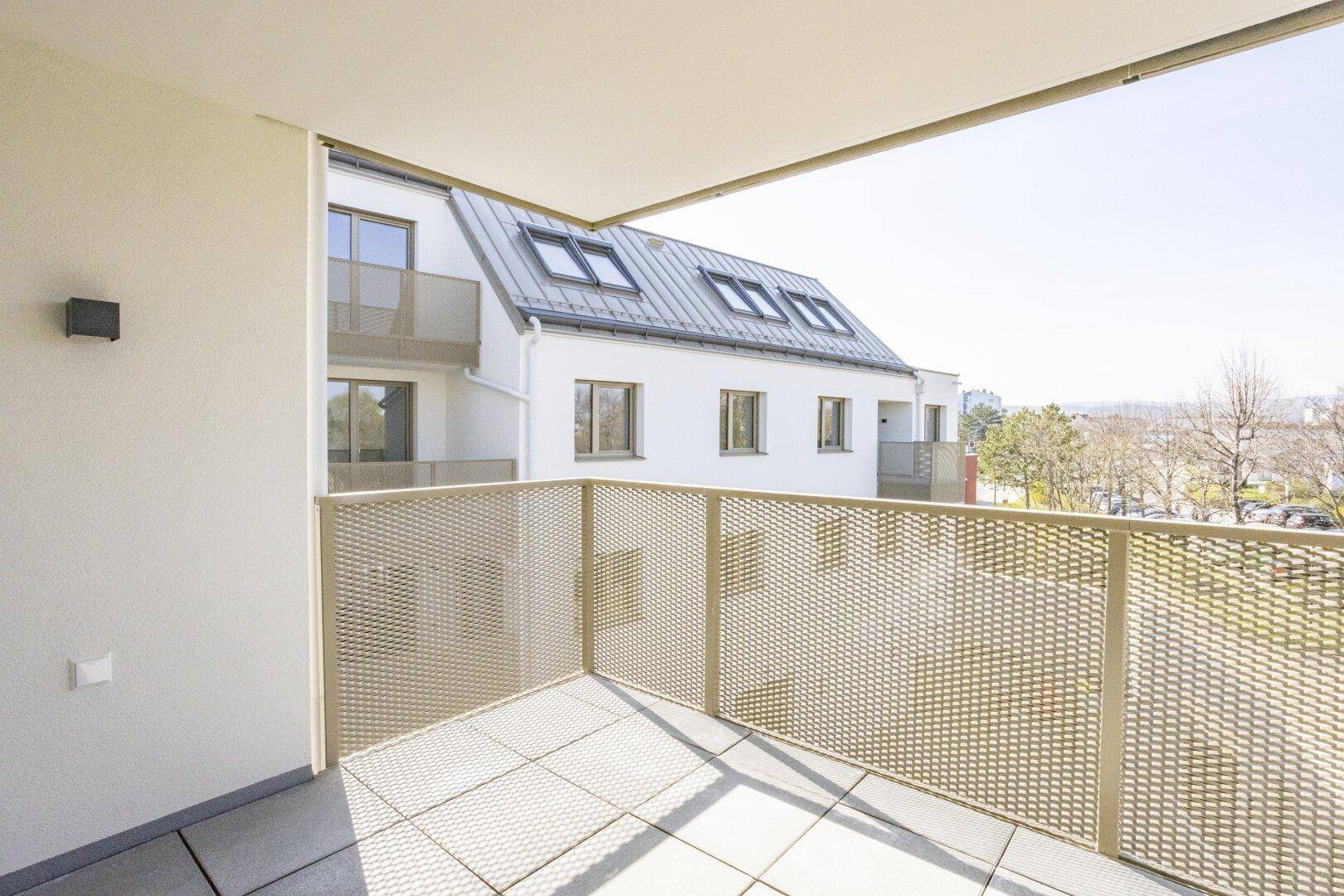 Heller Balkon mit Blick auf die umliegenden Neubauten und den Himmel.