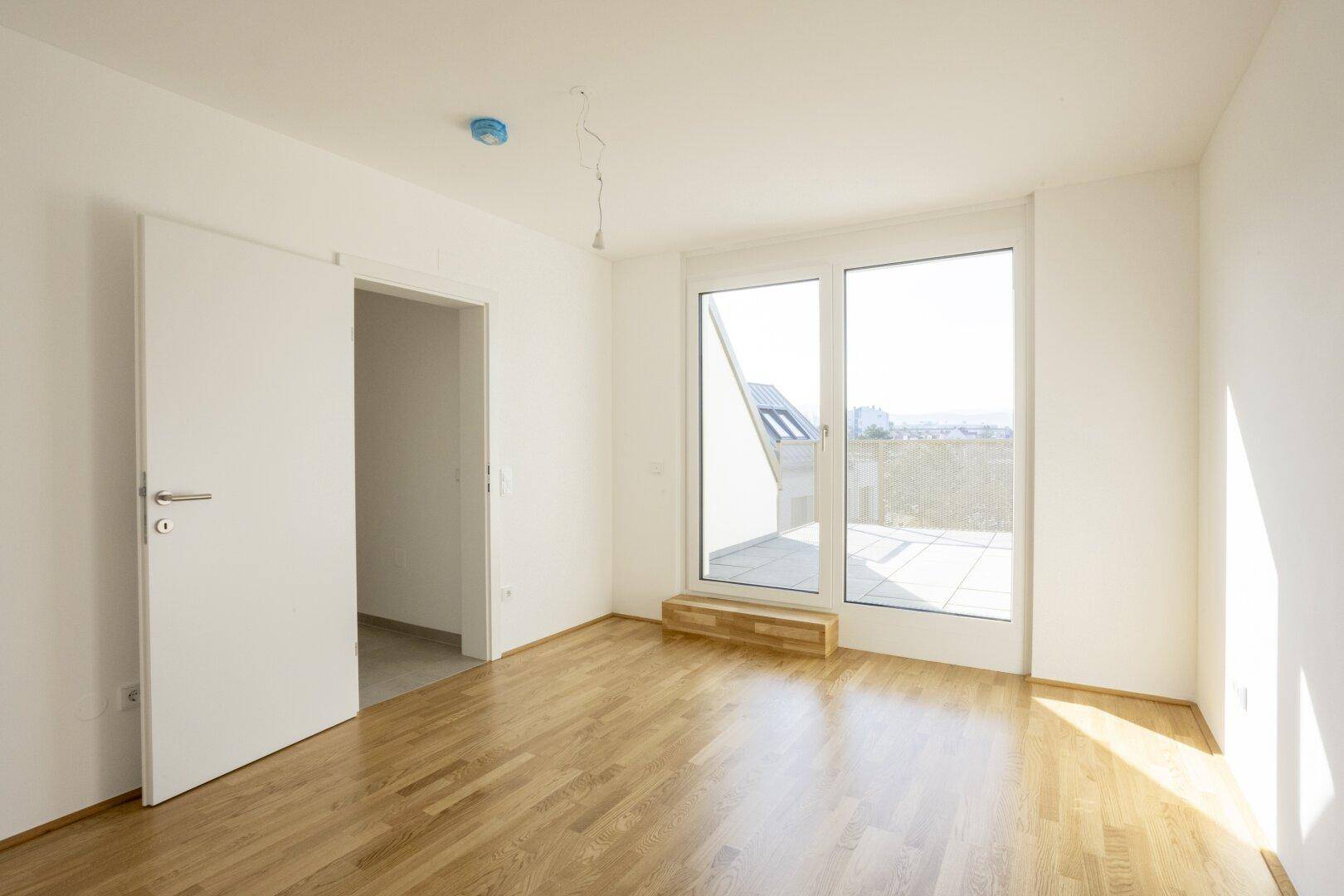 Helles Schlafzimmer mit Holzboden und direktem Zugang zu einer sonnigen Terrasse.