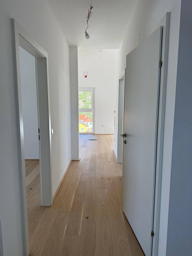 Langer, heller Flur mit Holzboden und mehreren Türen zu angrenzenden Räumen.