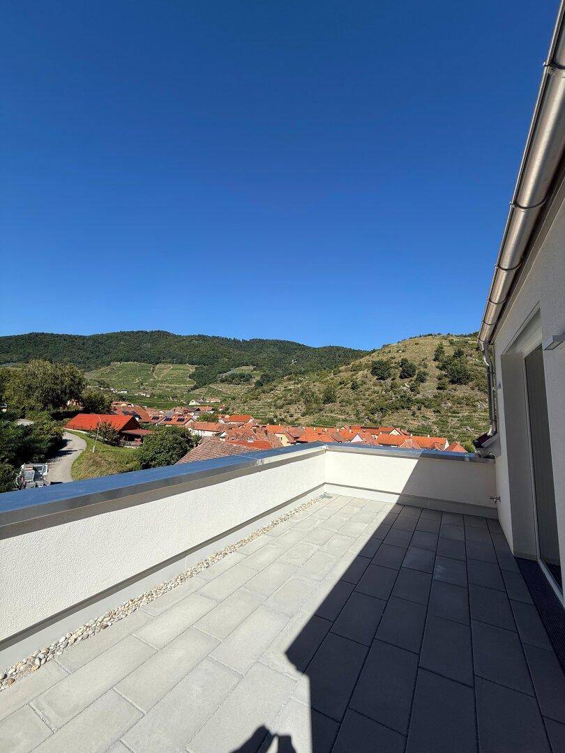 Große Terrasse mit Fliesenboden und weitem Blick auf die umliegende Landschaft und Weinberge.
