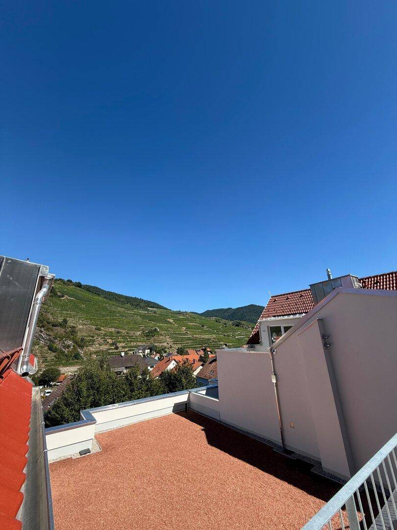 Sonnige Dachterrasse mit weitem Blick über Weinberge und die umliegende Landschaft.
