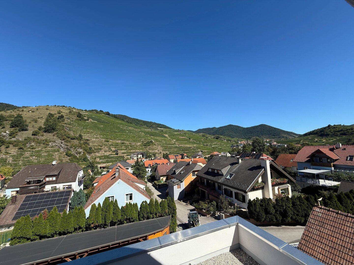 Panoramablick von der Terrasse auf die umliegende Landschaft mit Weinbergen und Wohnhäusern.