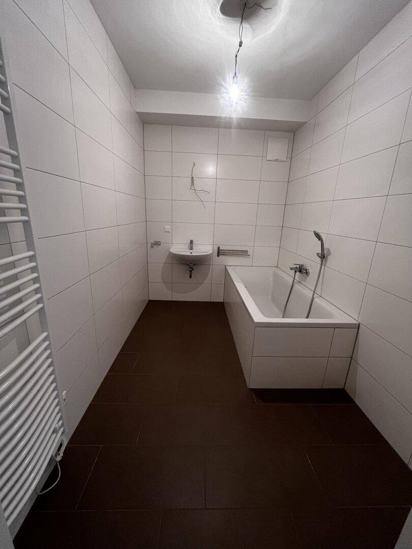 Modern gefliestes Badezimmer mit Badewanne, Waschbecken und beheiztem Handtuchhalter.