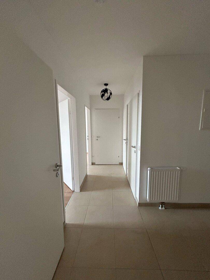 Langer, heller Flur mit Fliesenboden und mehreren Türen, der verschiedene Räume verbindet.