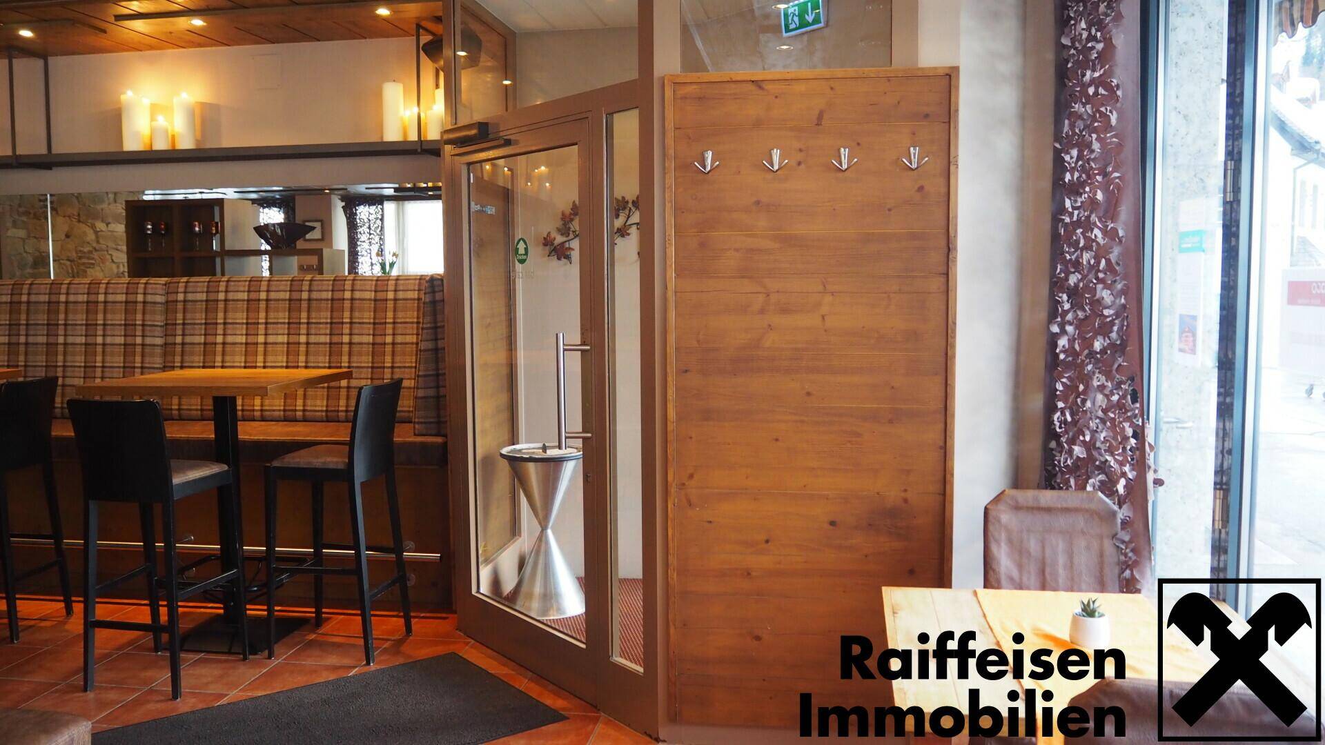 Eingangsbereich mit Glastür, Garderobe und karierten Sitzbänken, die den rustikalen Stil des Restaurants fortsetzen.