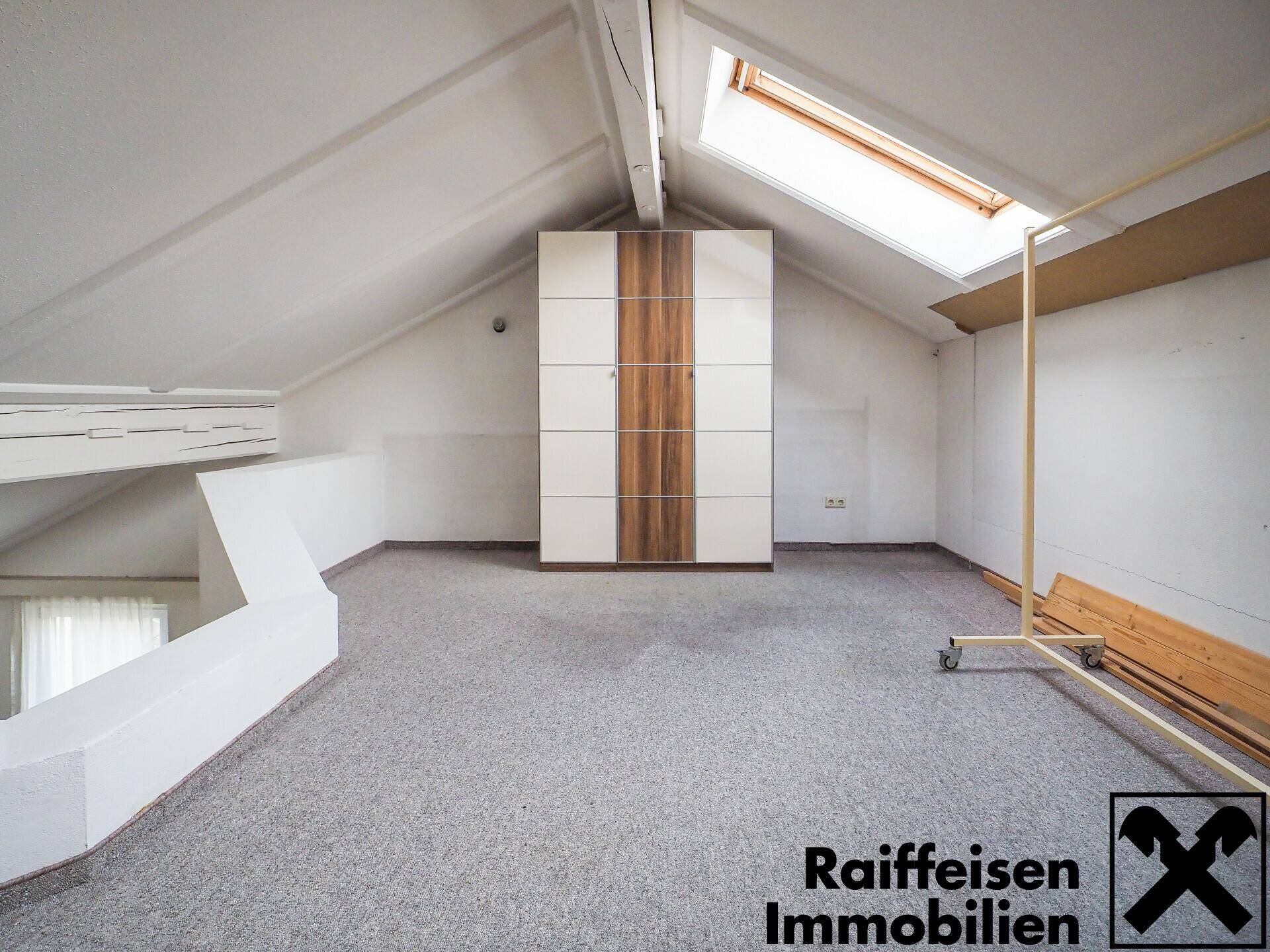 Dachzimmer mit Teppichboden, Dachschrägen, Oberlicht und einem großen Kleiderschrank.