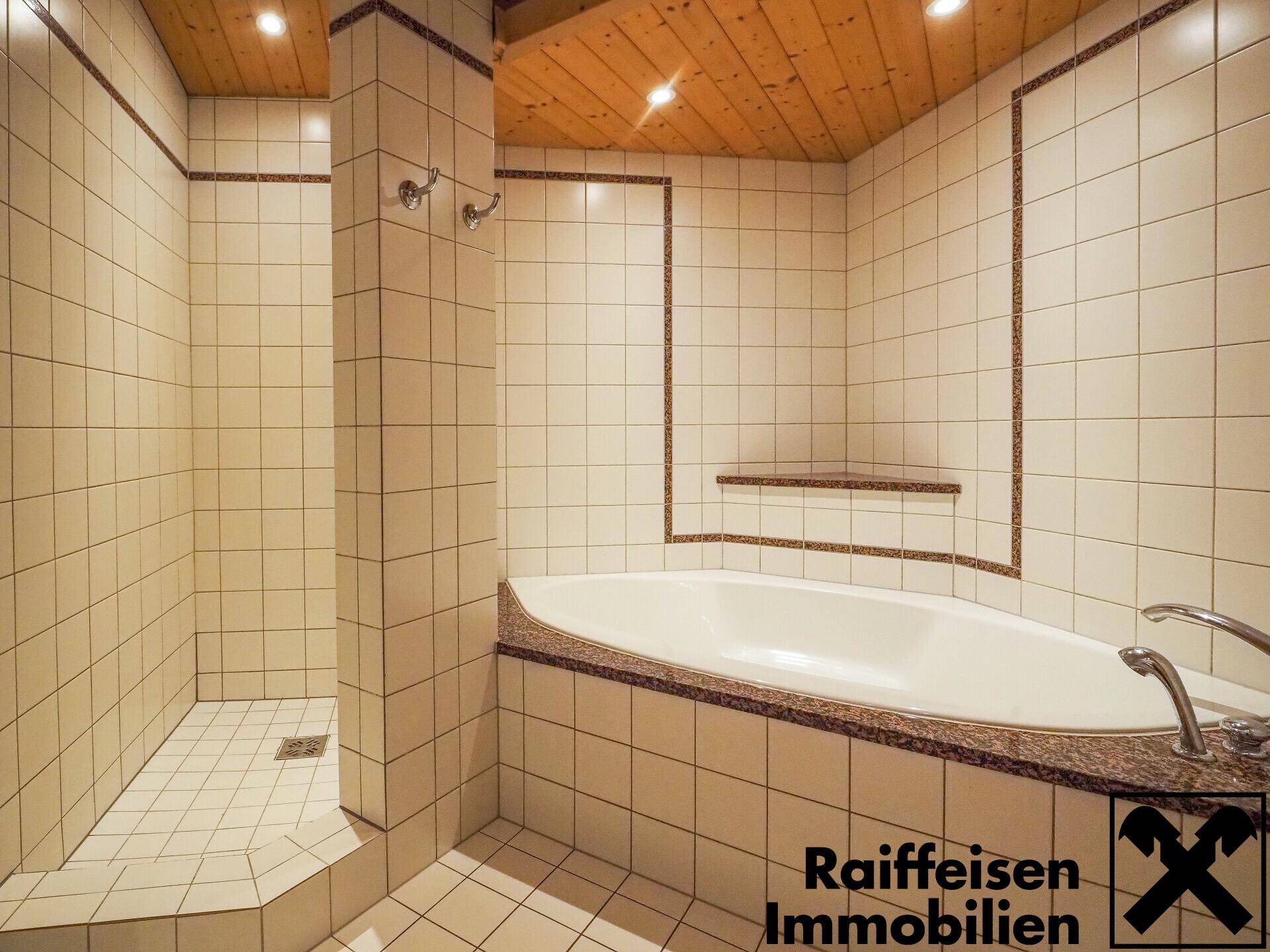 Gefliestes Badezimmer mit Eckbadewanne, separater Dusche und Holzdecke, in hellem Design.