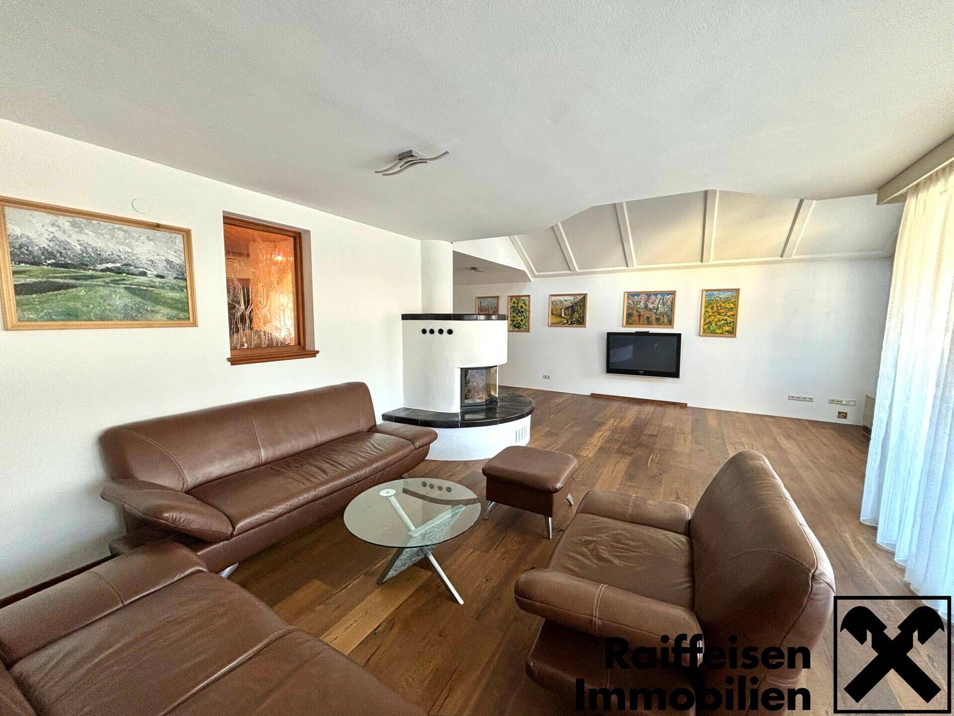Geräumiges Wohnzimmer mit Ledersofas, modernem Kamin, Holzboden und Dachschrägen mit Oberlichtern.