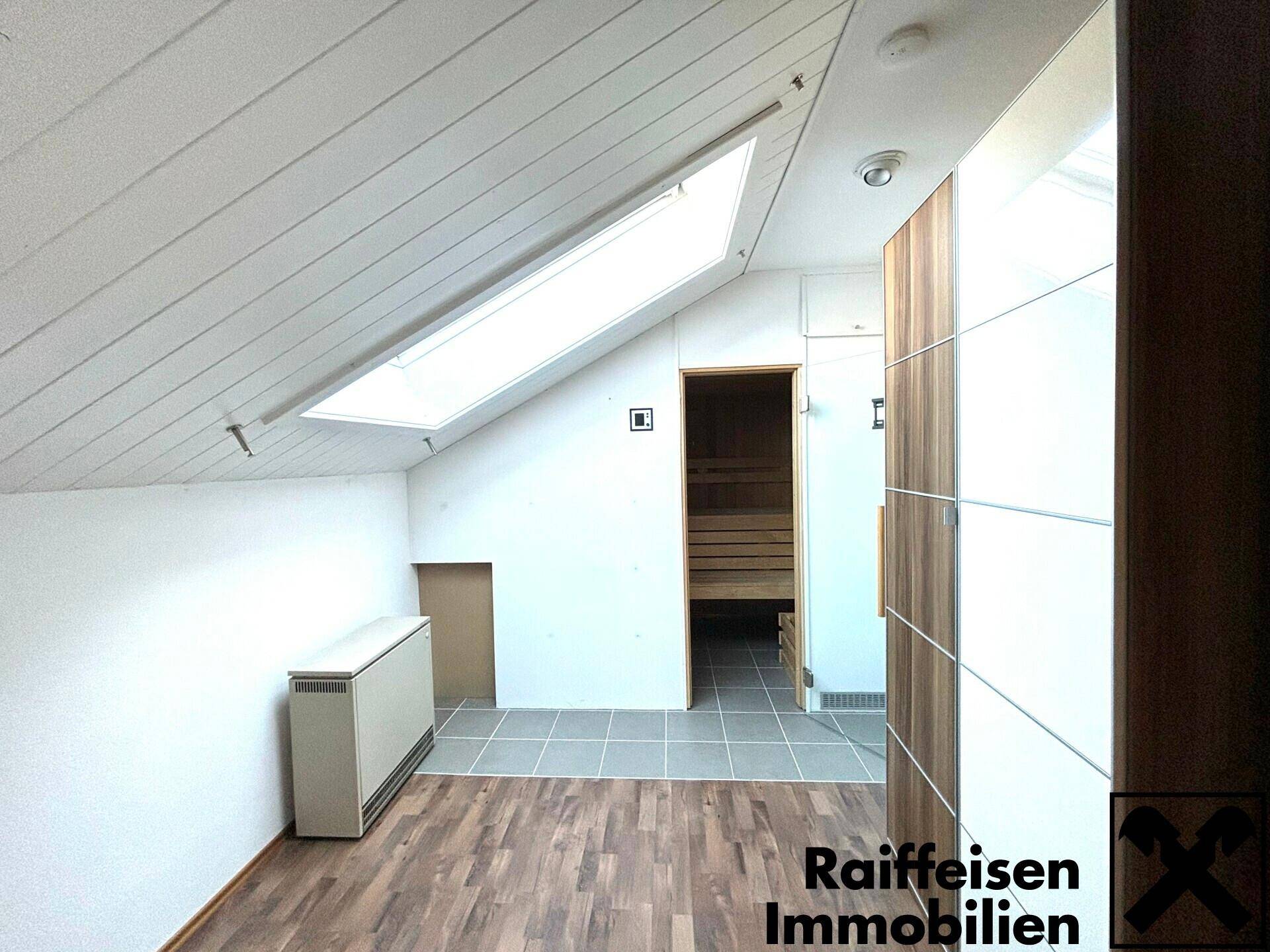 Heller Raum mit Dachschrägen, Oberlicht und direktem Zugang zu einer Sauna.