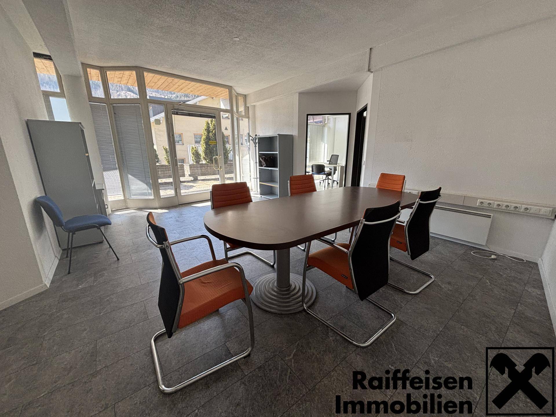 Geräumiger Büroraum mit großem Konferenztisch, modernen Stühlen und viel Tageslicht durch die Fenster.