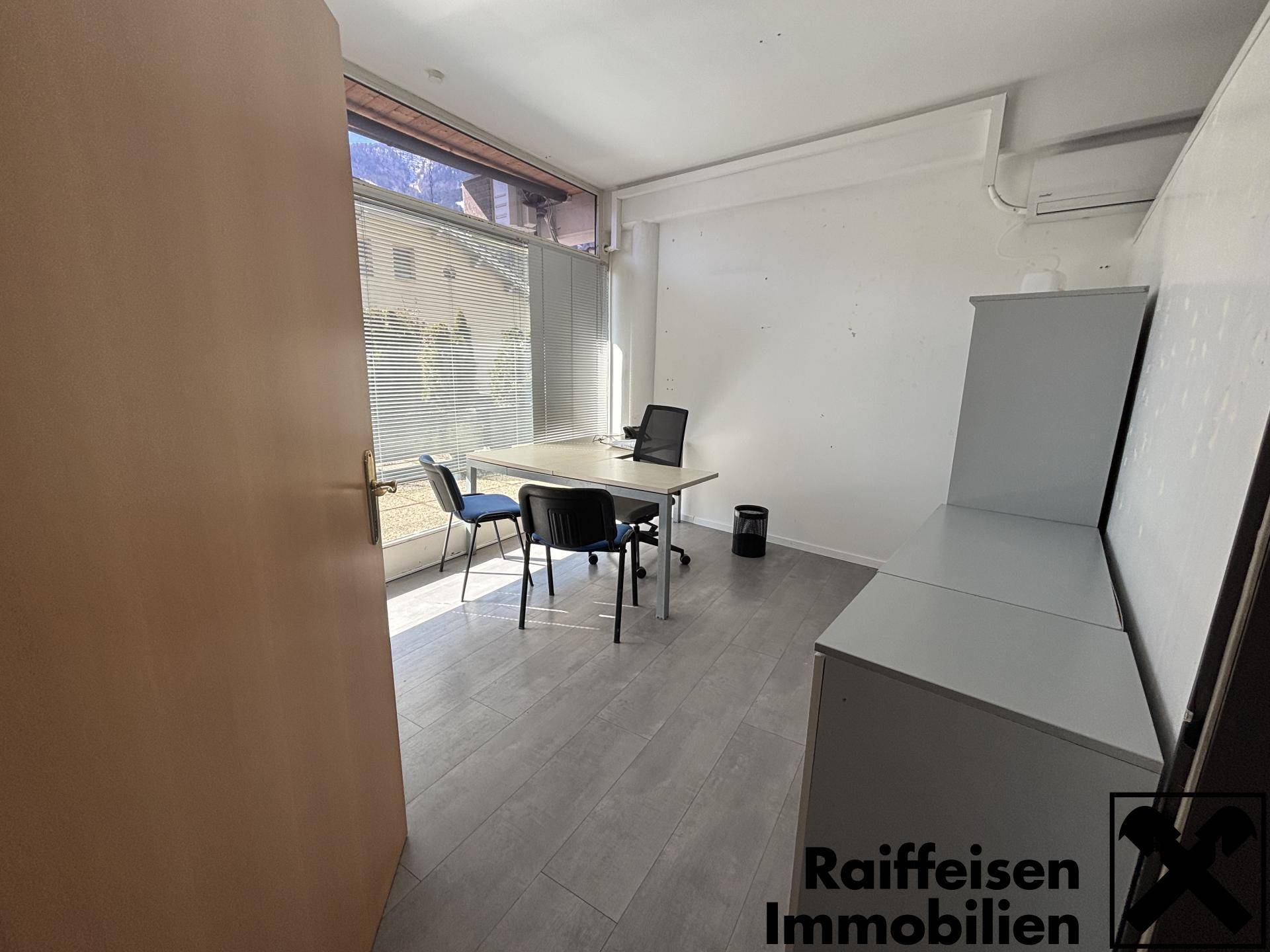 Helles Einzelbüro mit Schreibtisch, Bürostuhl und hellgrauem Laminatboden, gut beleuchtet durch ein großes Fenster.