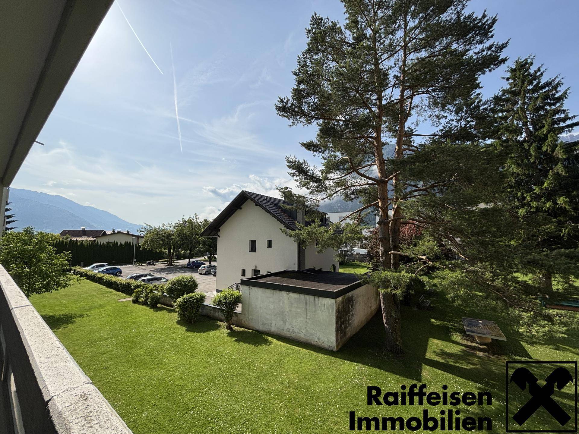 Weitläufiger Gartenbereich mit hohen Bäumen und Blick auf die umliegende Berglandschaft.