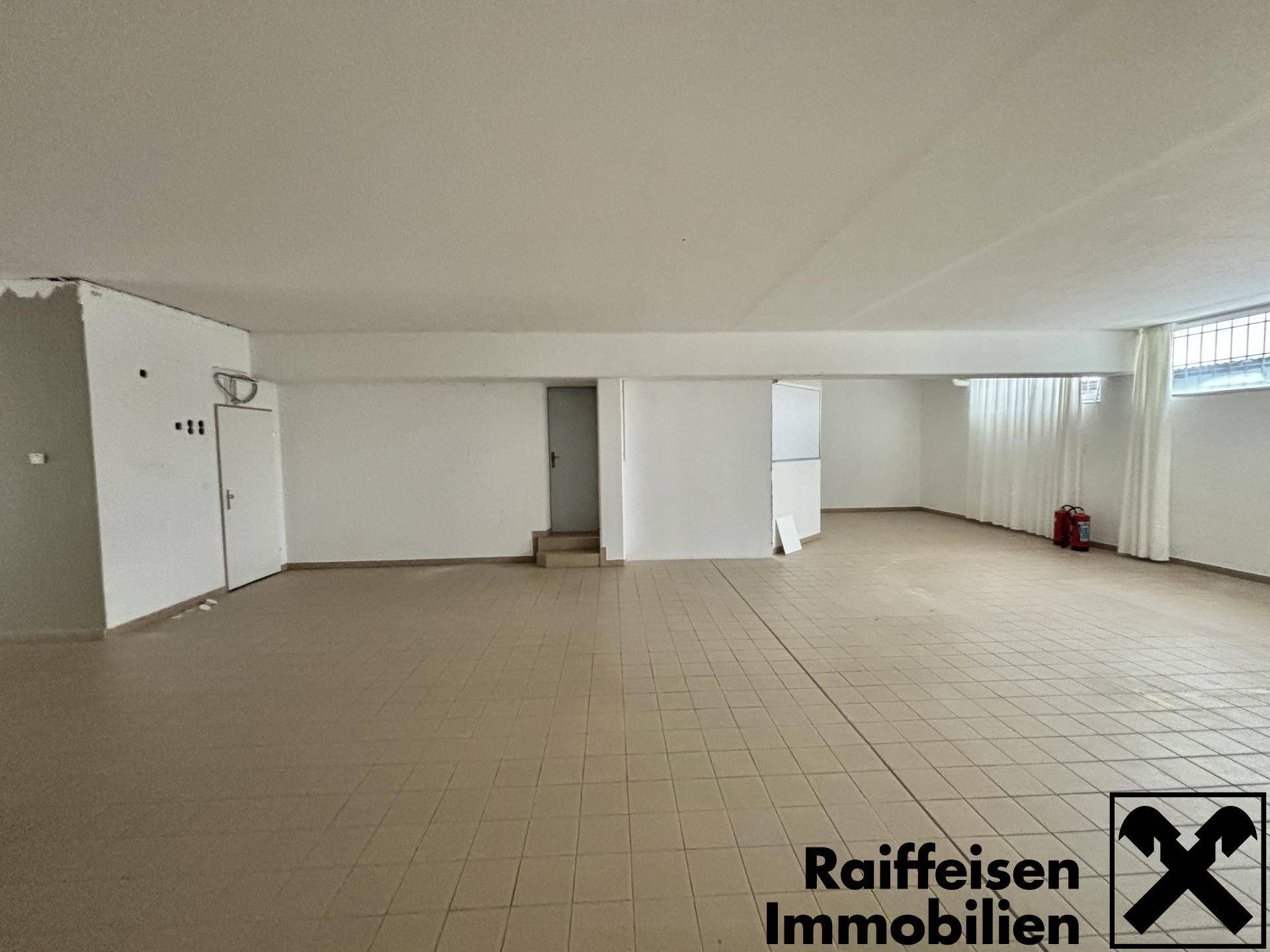 Weitläufiger, leerer Gewerberaum mit Fliesenboden und mehreren Türen, bereit zur individuellen Gestaltung.