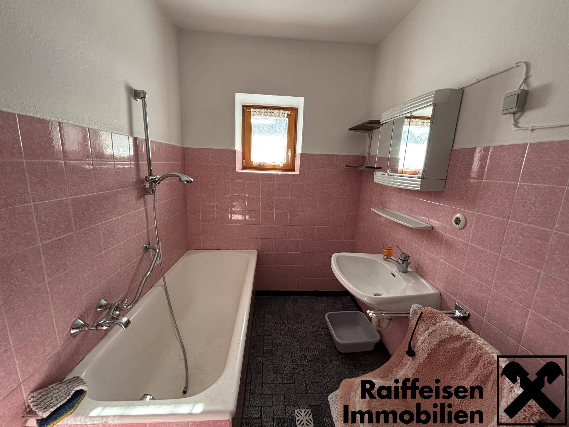 Badezimmer im Stil der 80er Jahre mit rosa Fliesen, Badewanne und kleinem Fenster.