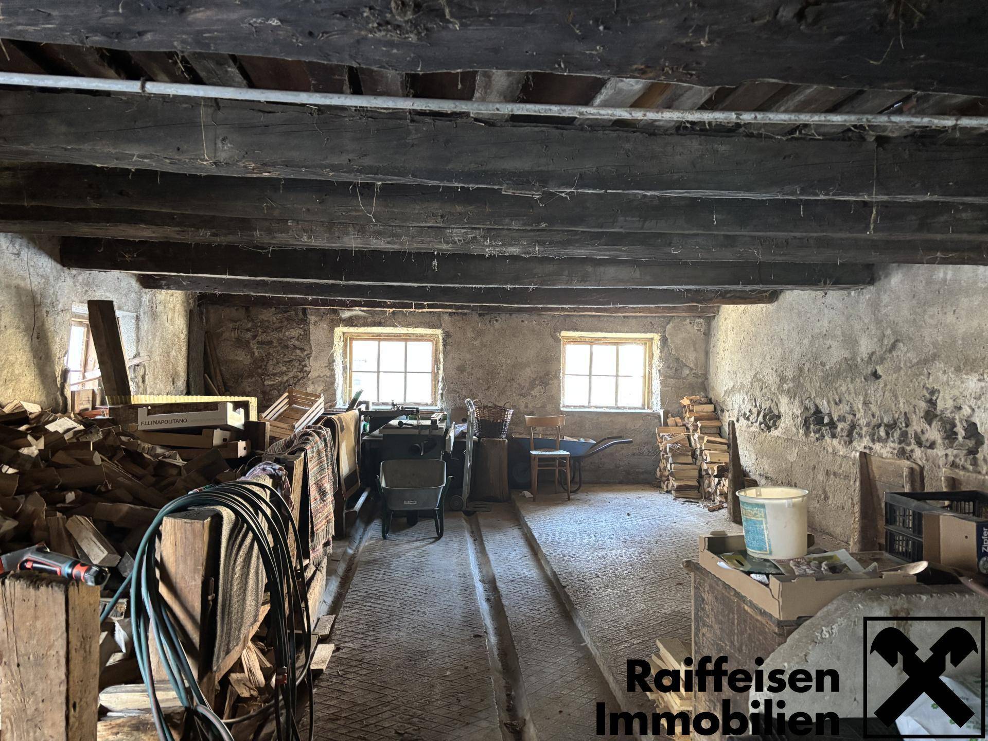 Großer Lagerraum im Nebengebäude mit Holzbalkendecke und Werkzeugen.
