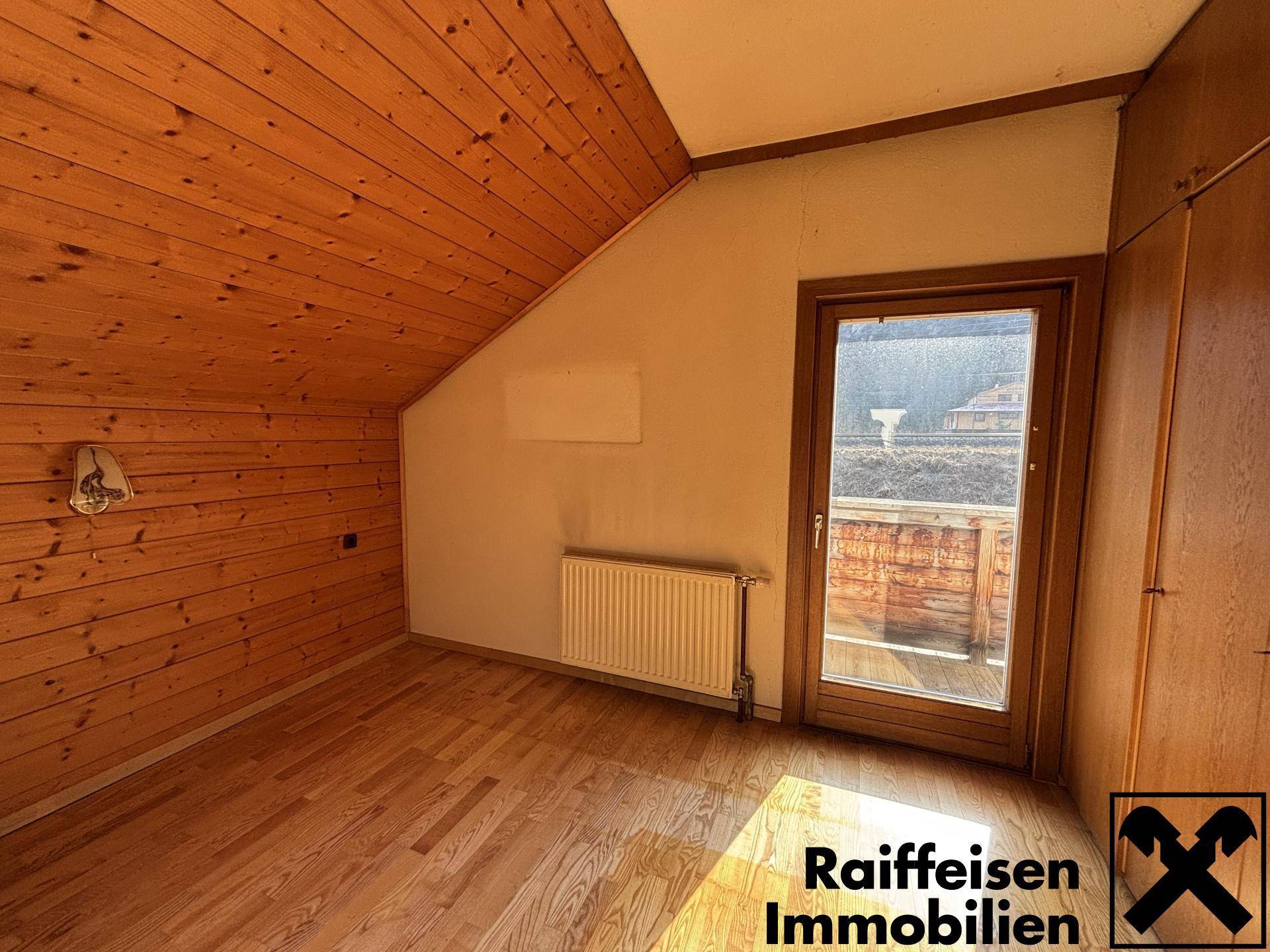 Helles Dachschlafzimmer mit Holzdecke und direktem Zugang zum Balkon.
