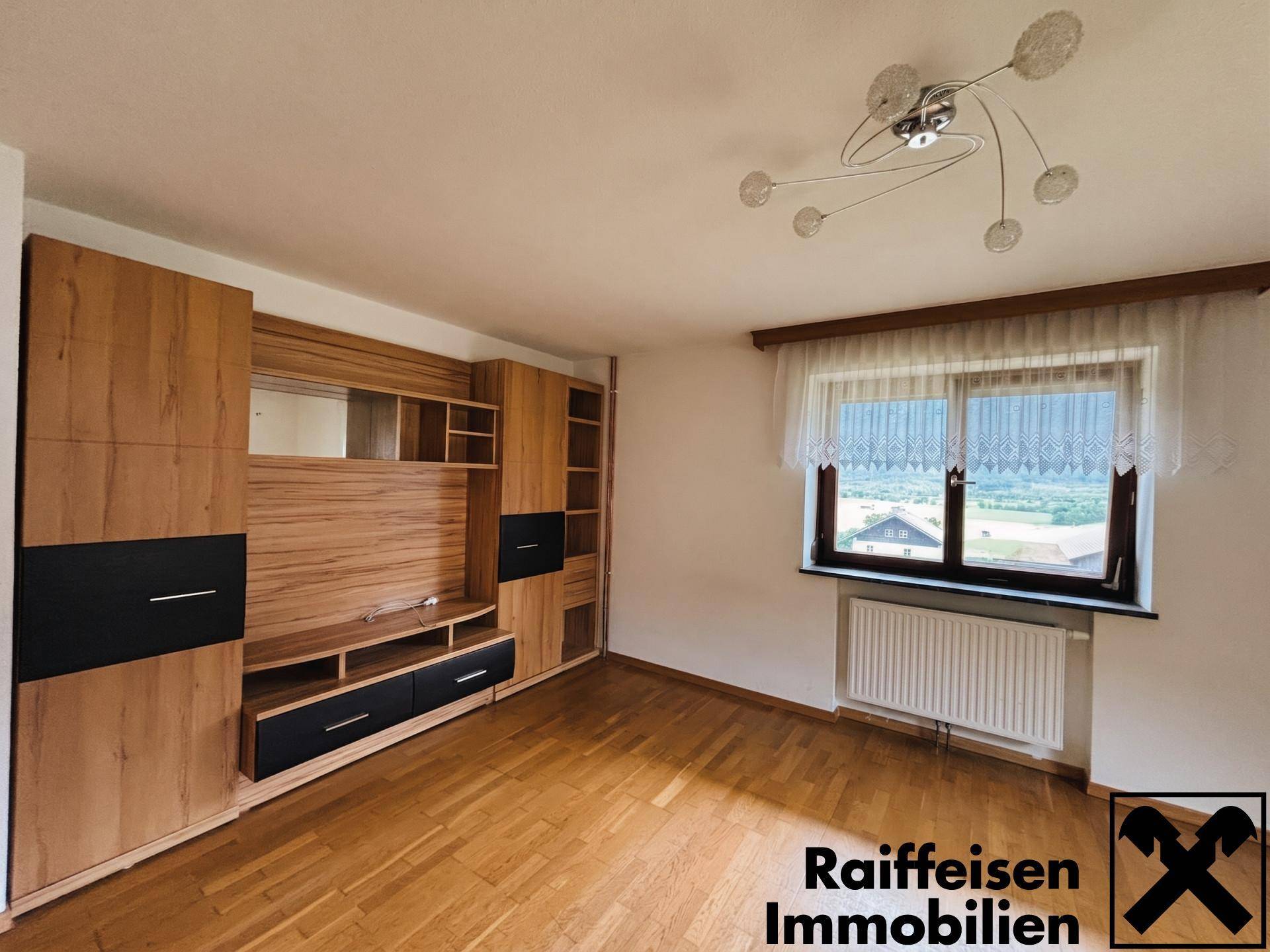 Helles Wohnzimmer mit moderner Holz-Wohnwand und großem Fenster mit Panoramablick.