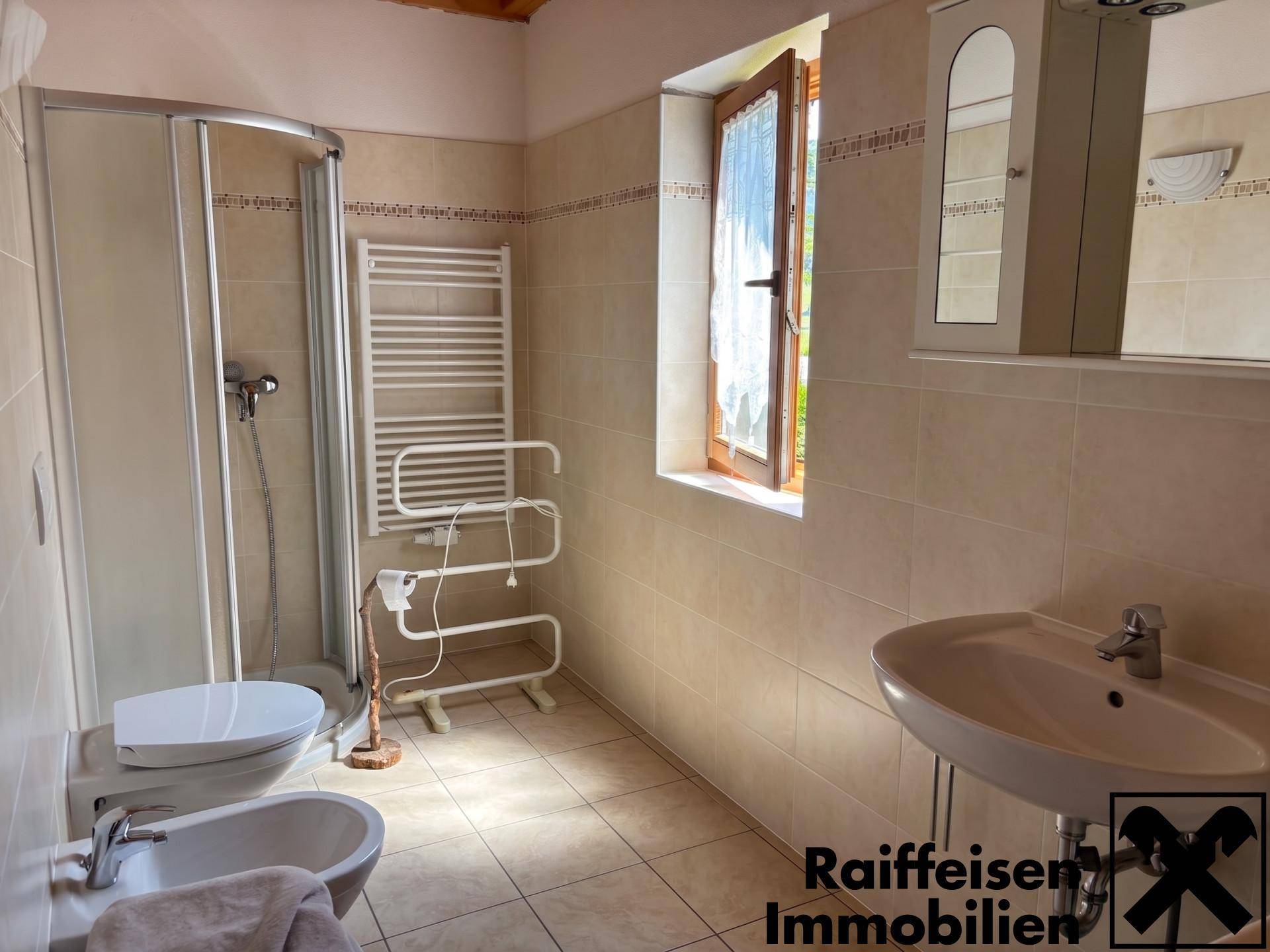 Badezimmer mit Dusche, WC, Bidet und Fenster, ausgestattet mit einem Spiegelschrank.