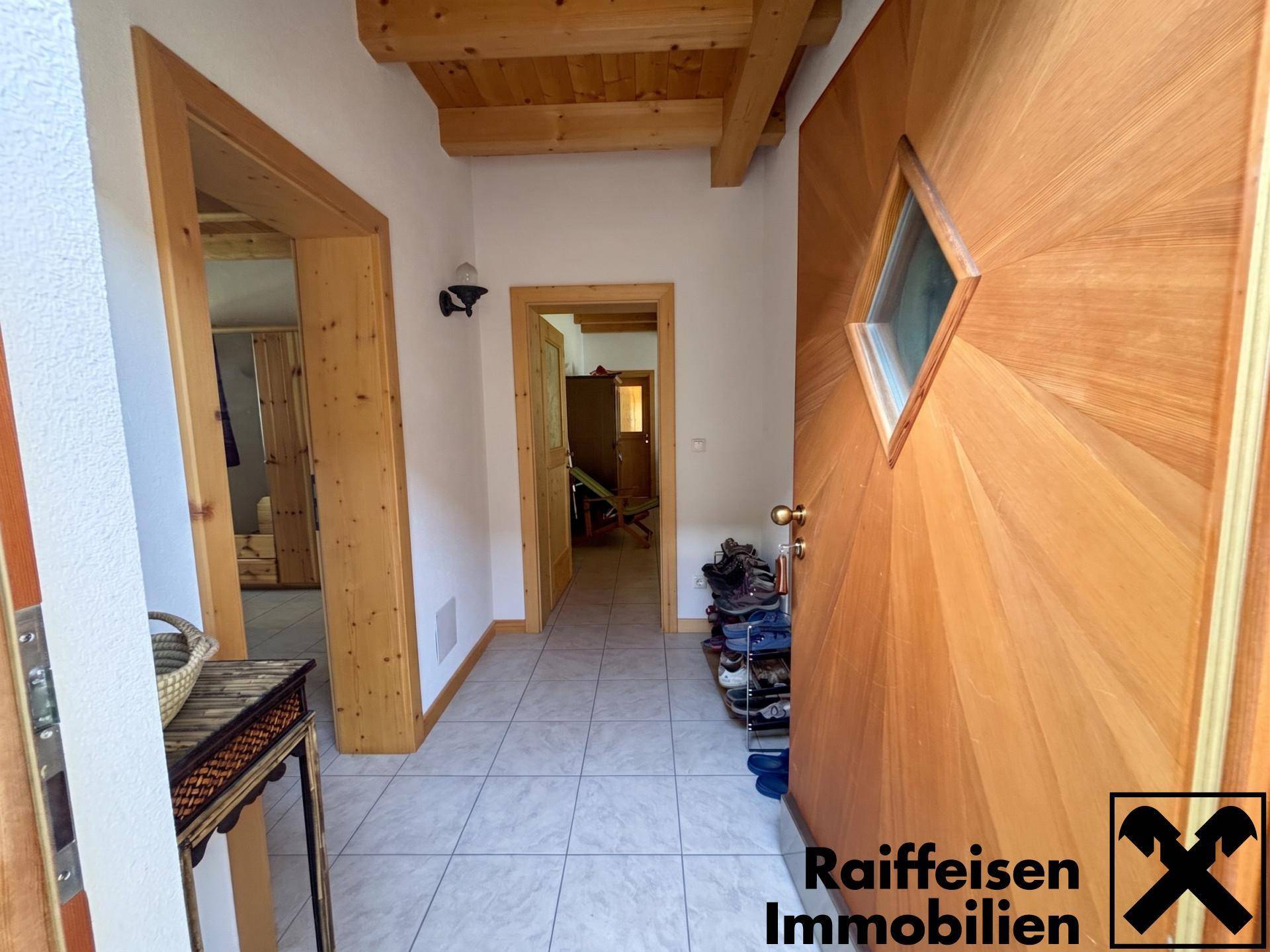Heller Eingangsbereich mit Holzdecke, Fliesenboden und rustikalen Holztüren.