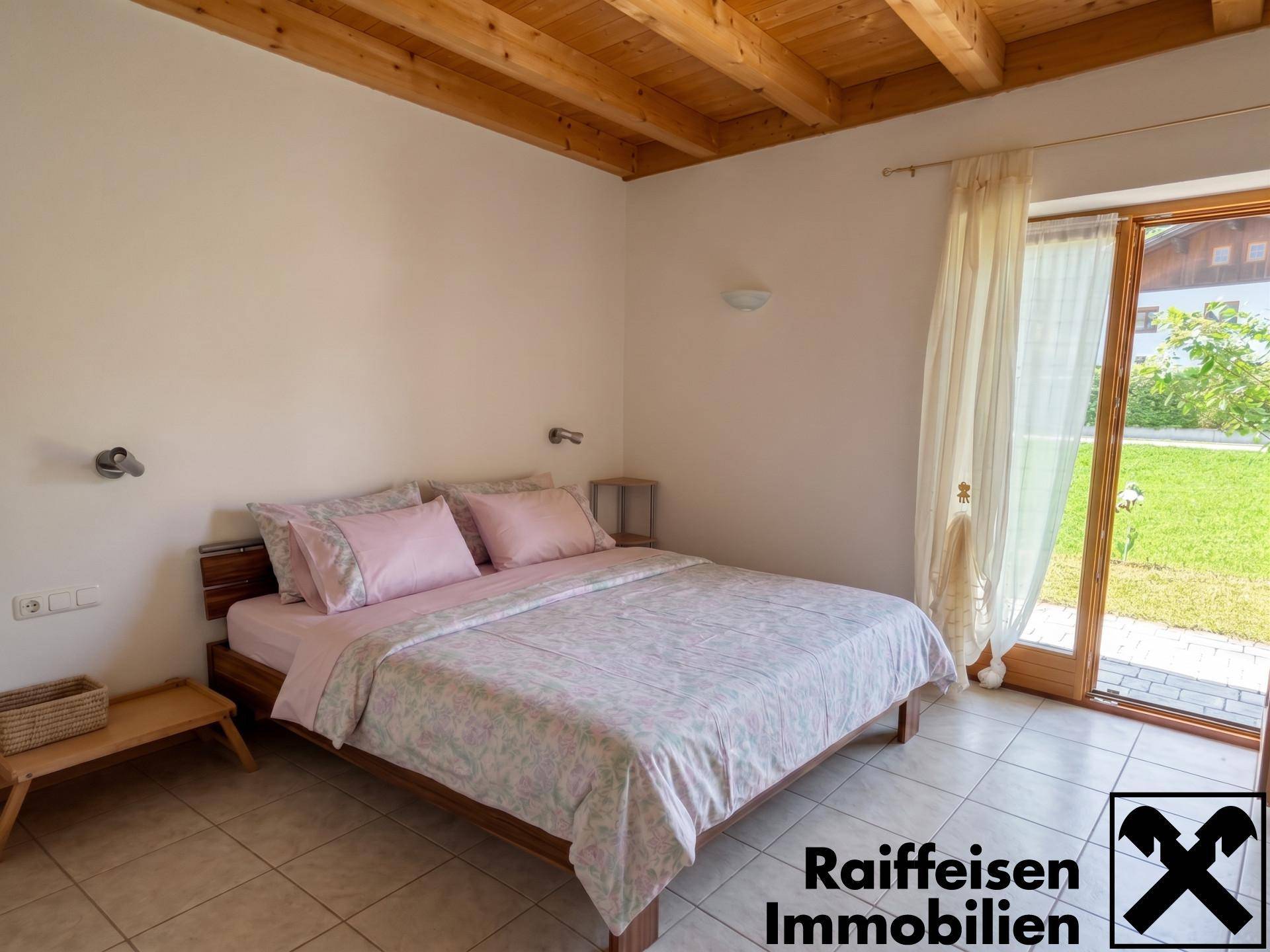 Schlafzimmer mit Holzbalkendecke, Fliesenboden und direktem Zugang zum Garten.