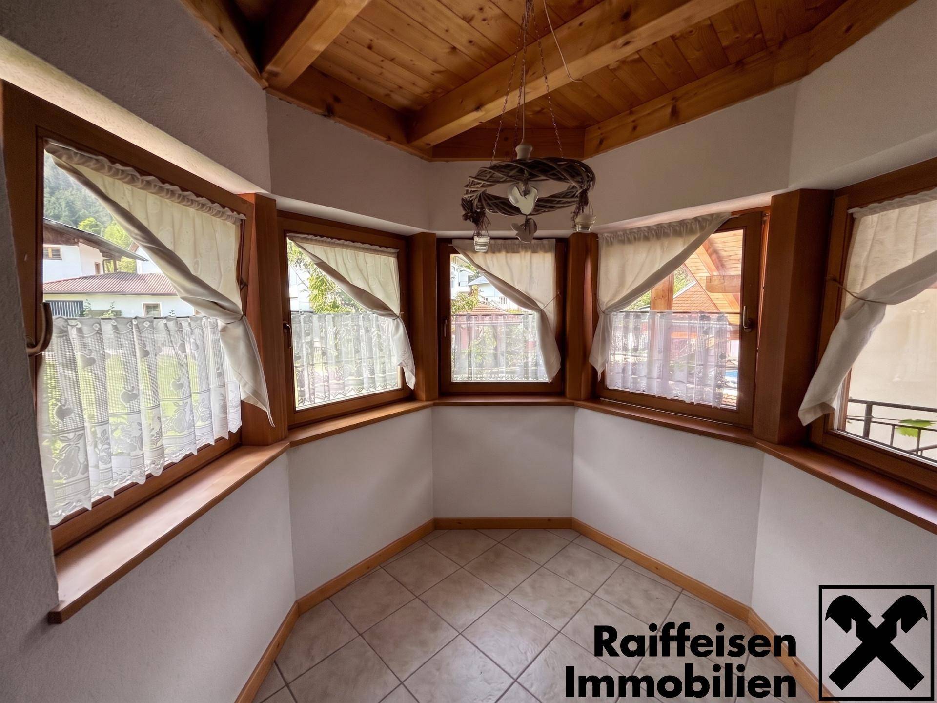 Erkerbereich mit vielen Fenstern, Fliesenboden und Holzbalkendecke, ideal für einen kleinen Essplatz.