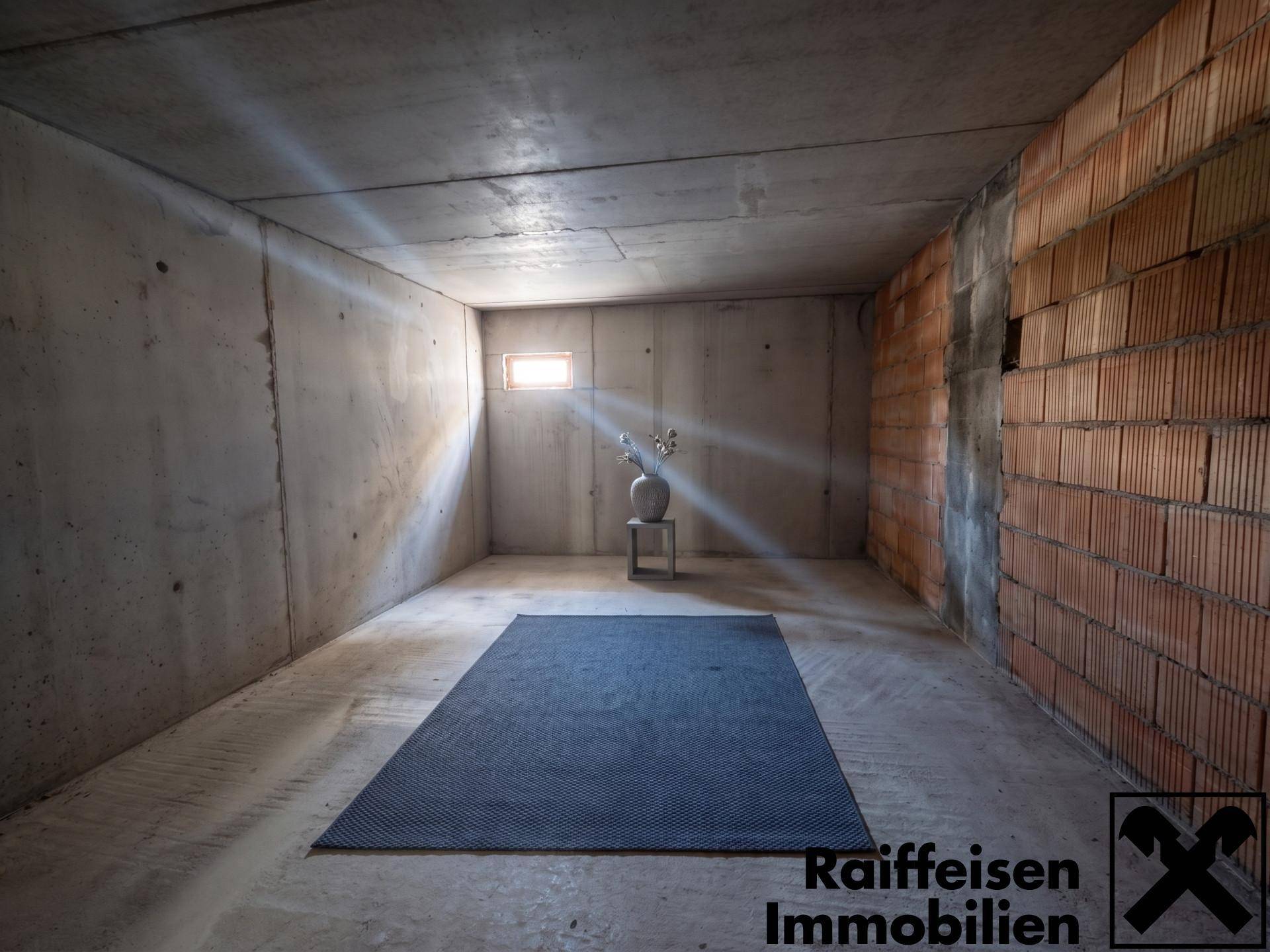 Unausgebauter Kellerraum mit Betonwänden und einem kleinen Fenster.