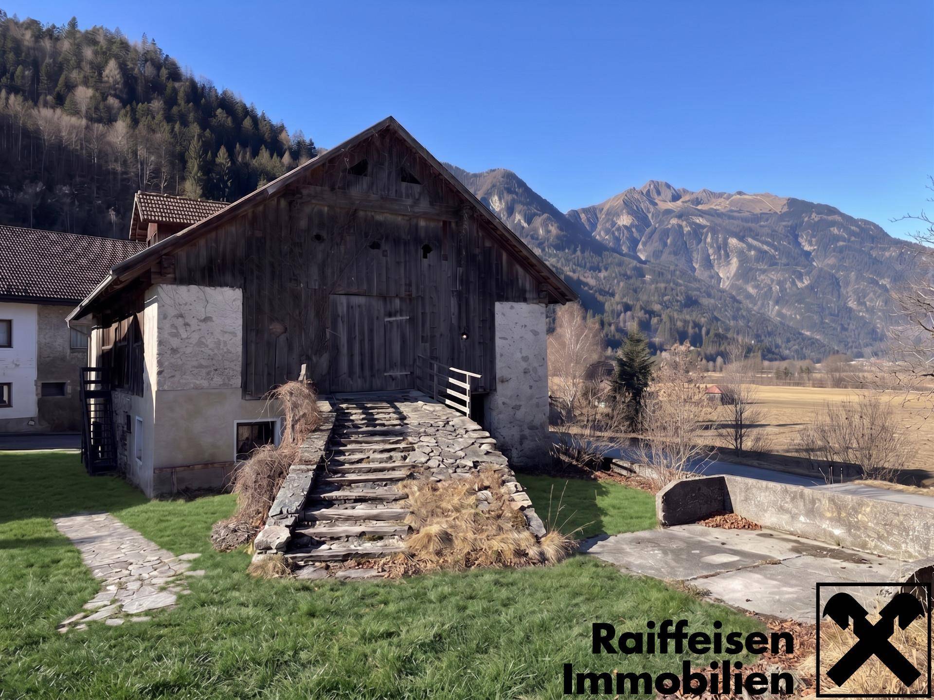 Rustikales Holzgebäude mit Steinfundament und alter Steintreppe, umgeben von grüner Natur und Bergen.