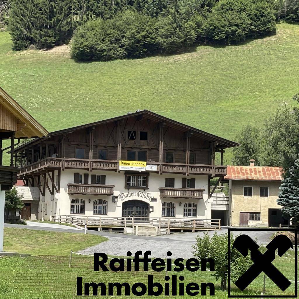 Traditionelles Gebäude im ländlichen Stil mit Holzbalkonen und grüner Umgebung, möglicherweise ein Gasthof.