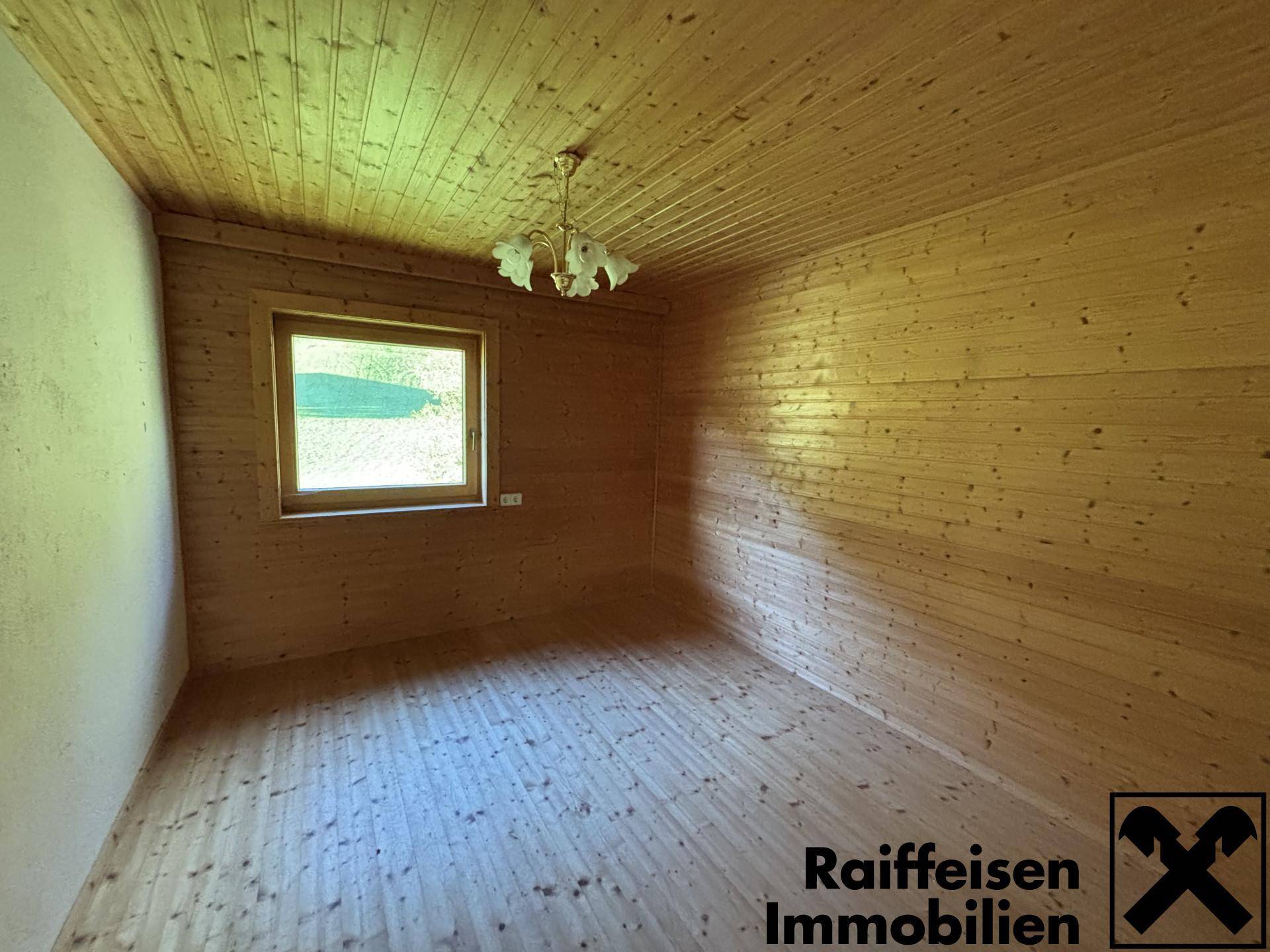 Gemütliches Zimmer mit Holztäfelung an Wänden und Decke sowie Holzdielenboden.