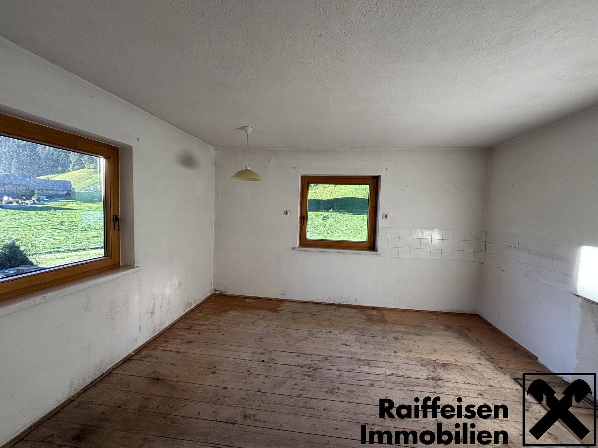Leerer Raum mit Holzdielenboden und gefliester Wandfläche, ideal für eine zukünftige Küche.