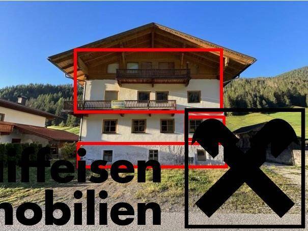 Traditionelles alpines Wohnhaus mit Holzbalkonen und markierten Bereichen in der Berglandschaft.