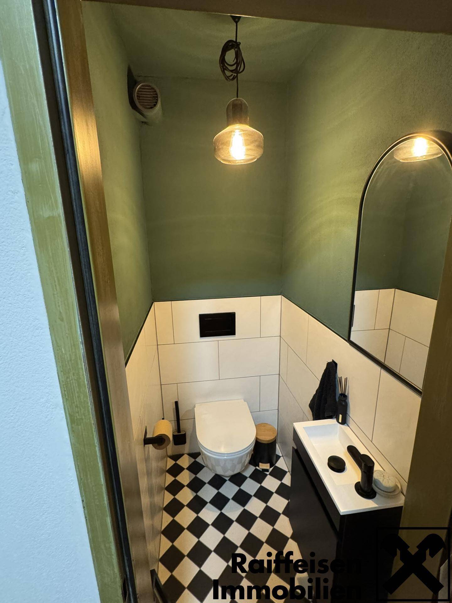 Stilvolles Gäste-WC mit Schachbrettmuster-Fliesen, modernem Waschtisch und grün gestrichenen Wänden.