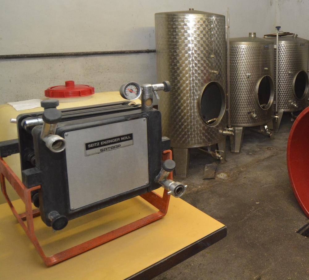 Raum mit großen Edelstahltanks und industriellen Geräten, wahrscheinlich zur Weinproduktion und Lagerung.