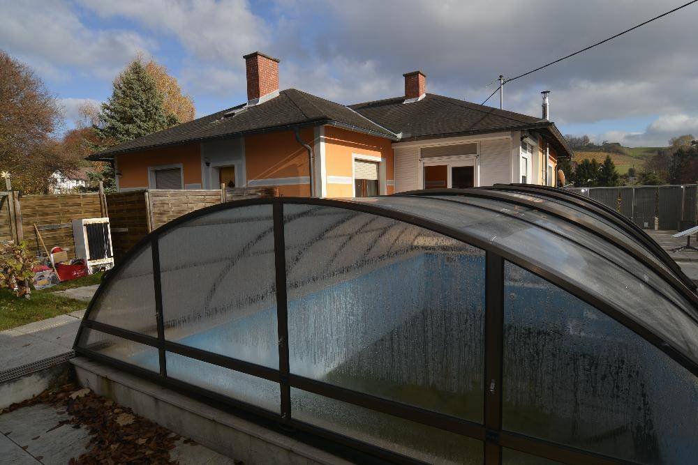 Rückansicht des Hauses mit überdachtem Pool und angrenzendem Gartenbereich.