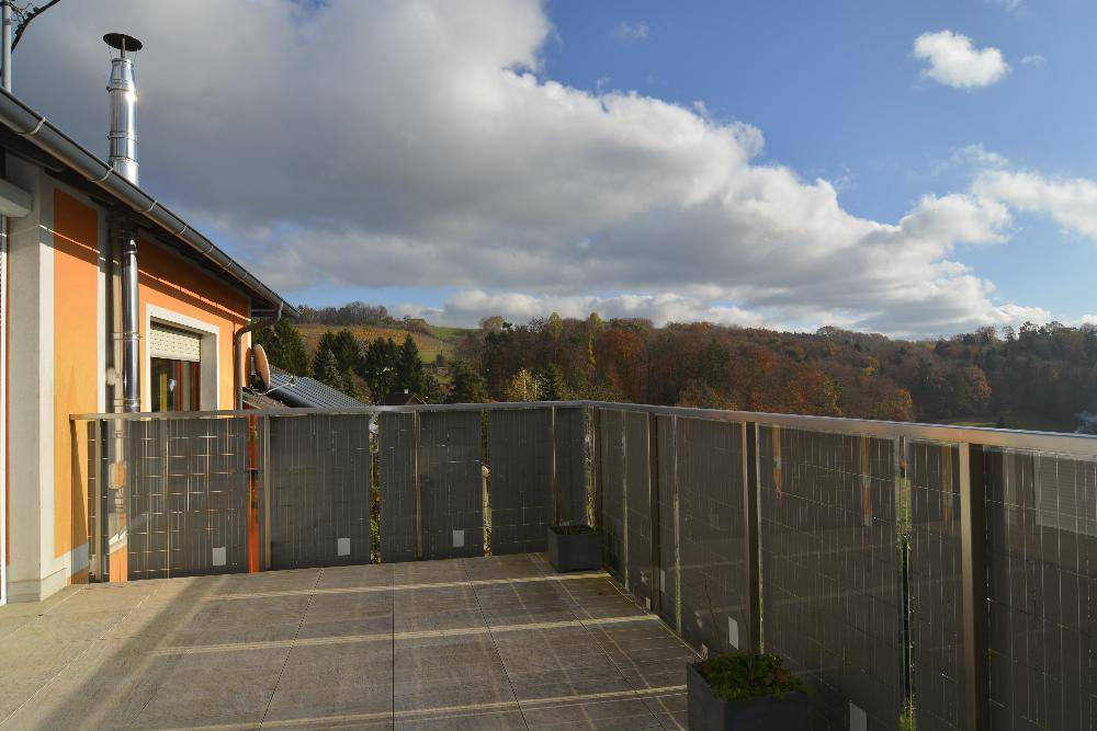 Geräumige Terrasse mit Metallgeländer und weitem Blick über die hügelige Landschaft.