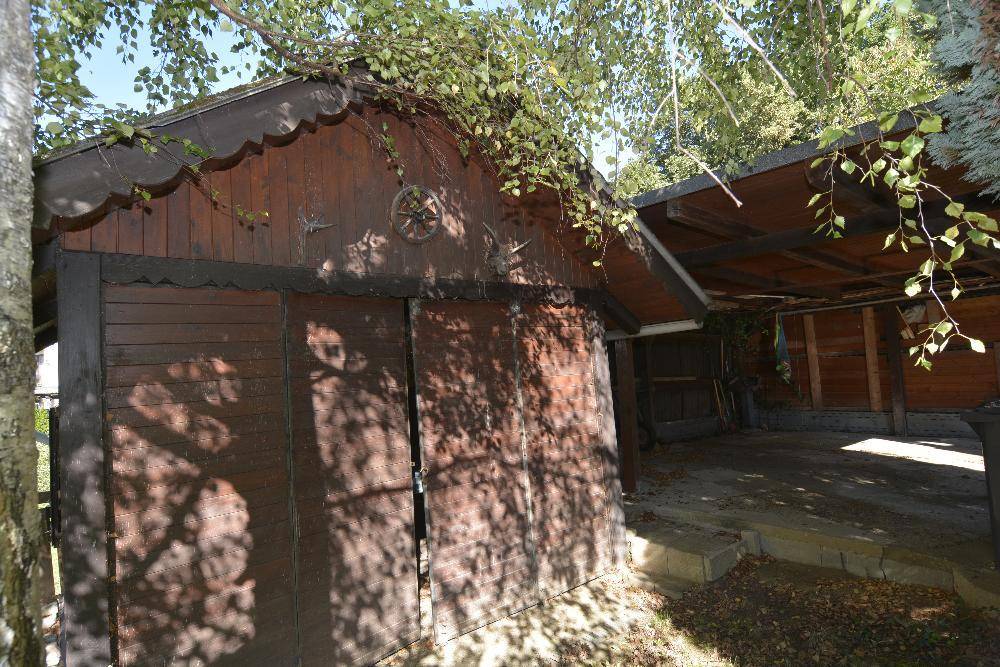 Rustikaler Holzschuppen und ein überdachter Carport im Gartenbereich des Anwesens.