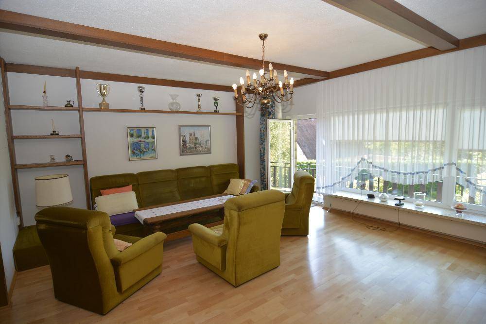 Gemütliches Wohnzimmer mit Holzdecke, Parkettboden und traditionellen Möbeln in Grüntönen.