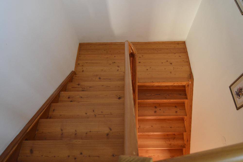 Holztreppe mit Geländer, die die verschiedenen Etagen des Hauses miteinander verbindet.