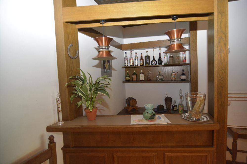 Hausbar mit Holzverkleidung, Regalen für Flaschen und dekorativer Beleuchtung.
