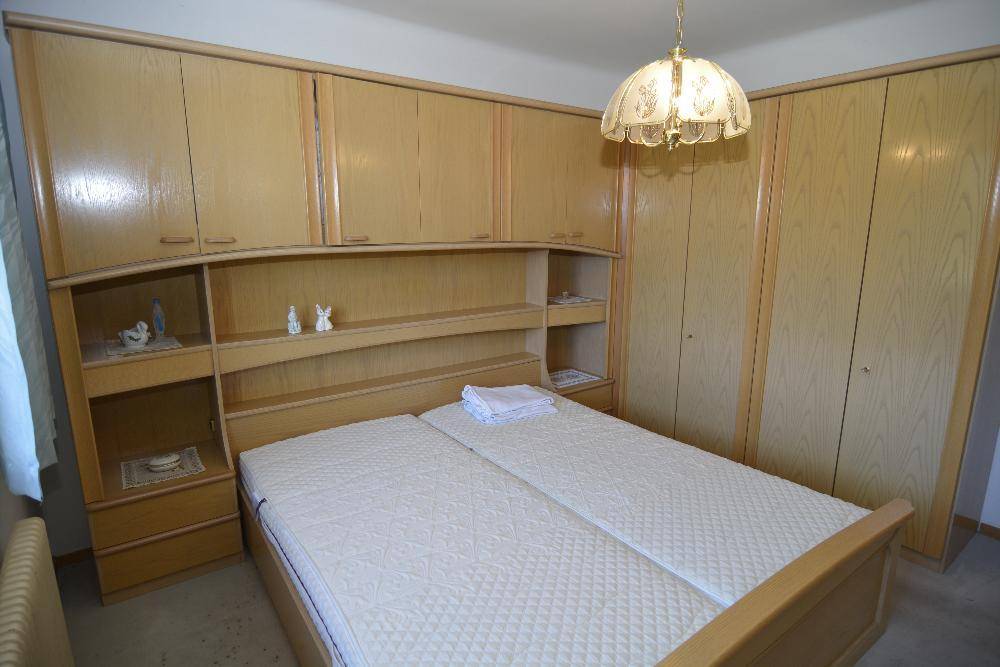 Schlafzimmer mit Doppelbett, Einbauschränken und hellen Holzmöbeln.
