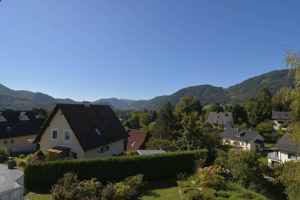 Panoramablick auf die umliegende grüne Hügellandschaft und die verstreuten Wohnhäuser.