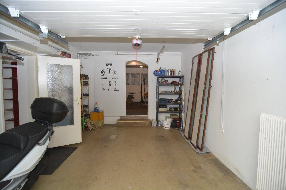 Geräumige Garage mit Platz für Fahrzeuge und Zugang zu einem Fitnessbereich.