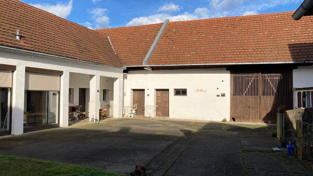 Weiterer Blick auf den Innenhof des Anwesens mit verschiedenen Gebäudeteilen und einem großen Tor.