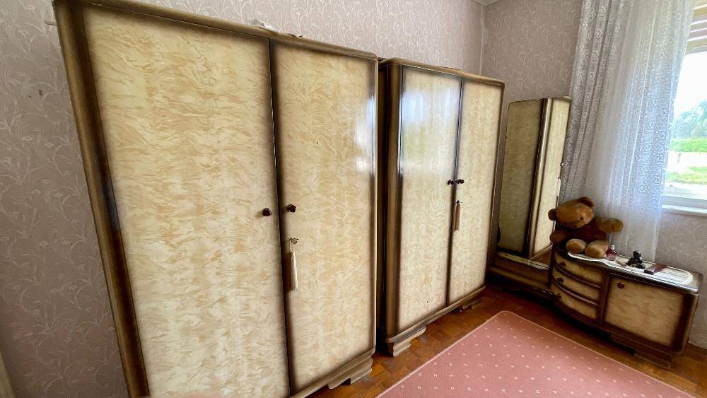 Schlafzimmer mit zwei Vintage-Kleiderschränken und einer Kommode mit einem Teddybären am Fenster.