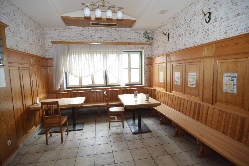 Traditioneller Essbereich mit Holzbänken, Holztischen und Fliesenboden.