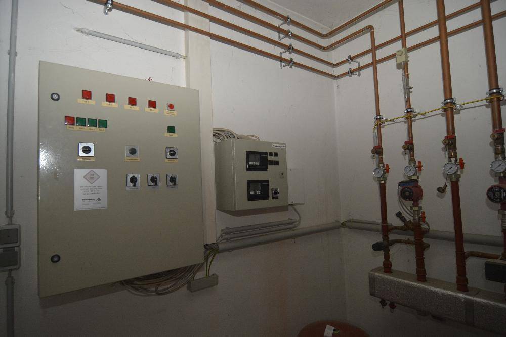 Technikraum mit einem elektrischen Schaltkasten und sichtbaren Kupferrohren an der Wand.