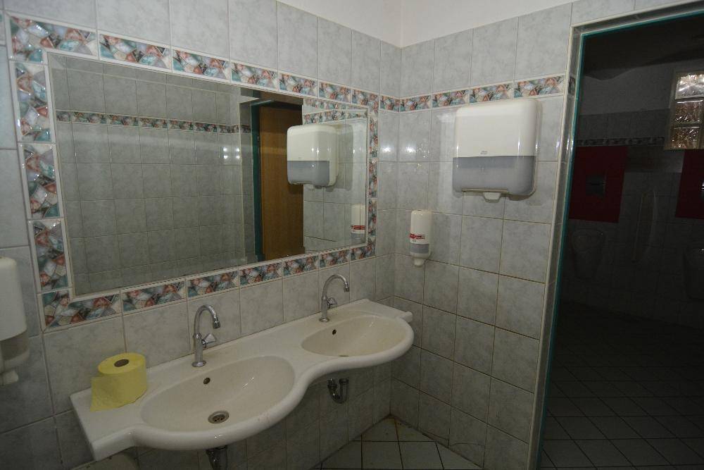 Badezimmer mit Doppelwaschbecken, großem Spiegel und hellen Fliesen, in einem funktionalen Design.