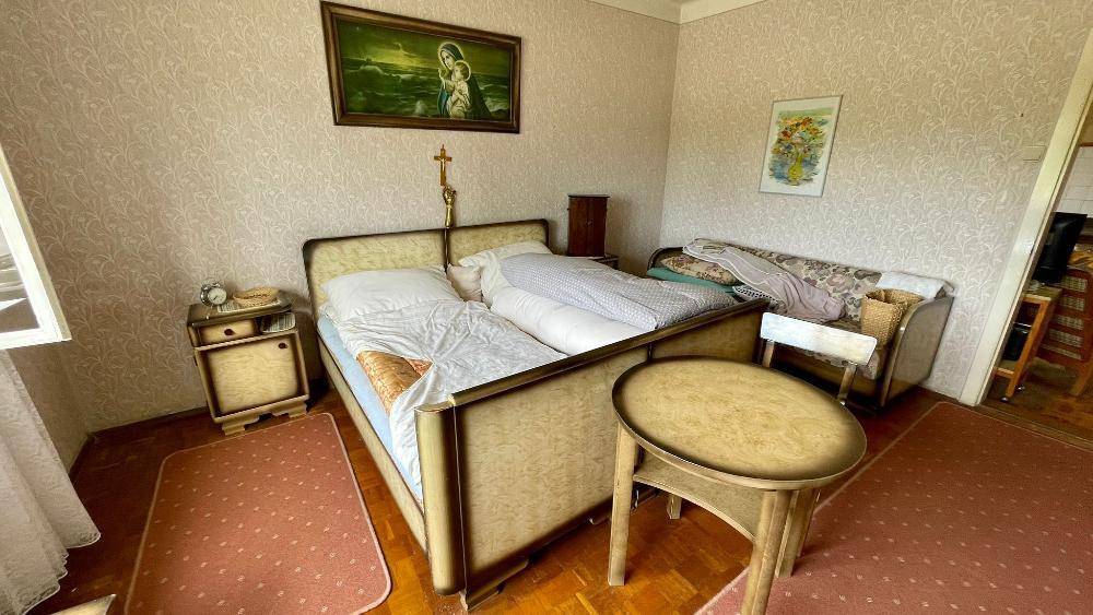 Schlafzimmer mit zwei Einzelbetten, Nachttisch und gemusterten Tapeten im Vintage-Stil.
