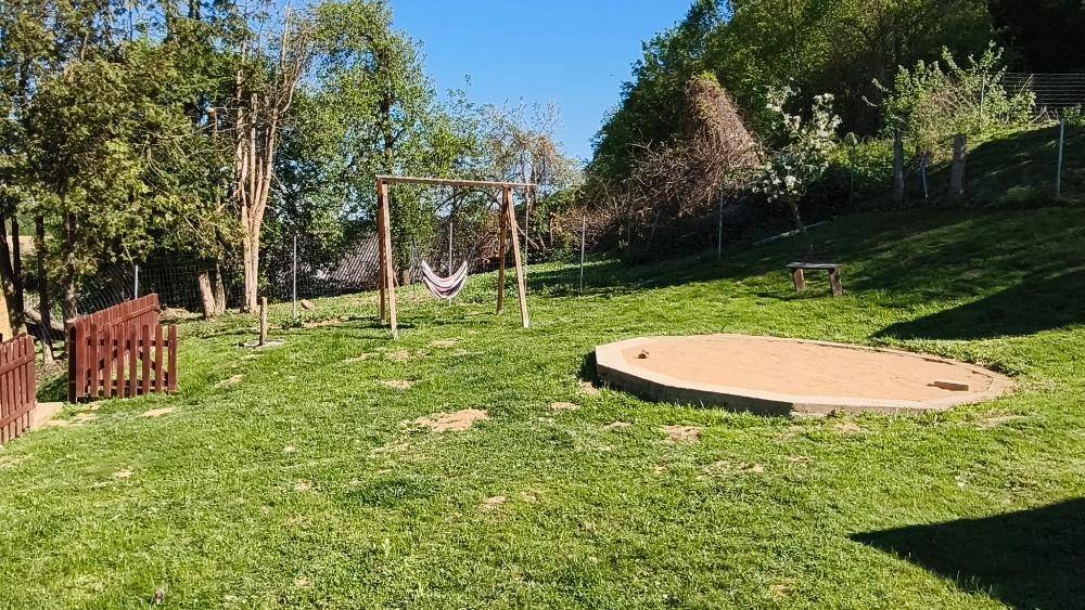 Großer Gartenbereich mit Schaukel und Sandkasten, ideal für Kinder zum Spielen.
